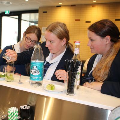 Three female students at a bar making mocktails 