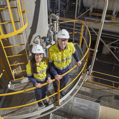 A male and female in high vis at a worksite looking up into the camera