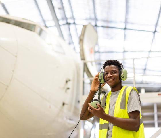 Student looking at camera in front of an airplane